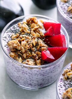 bowls of plum chia pudding with granola on a white table with fresh plums