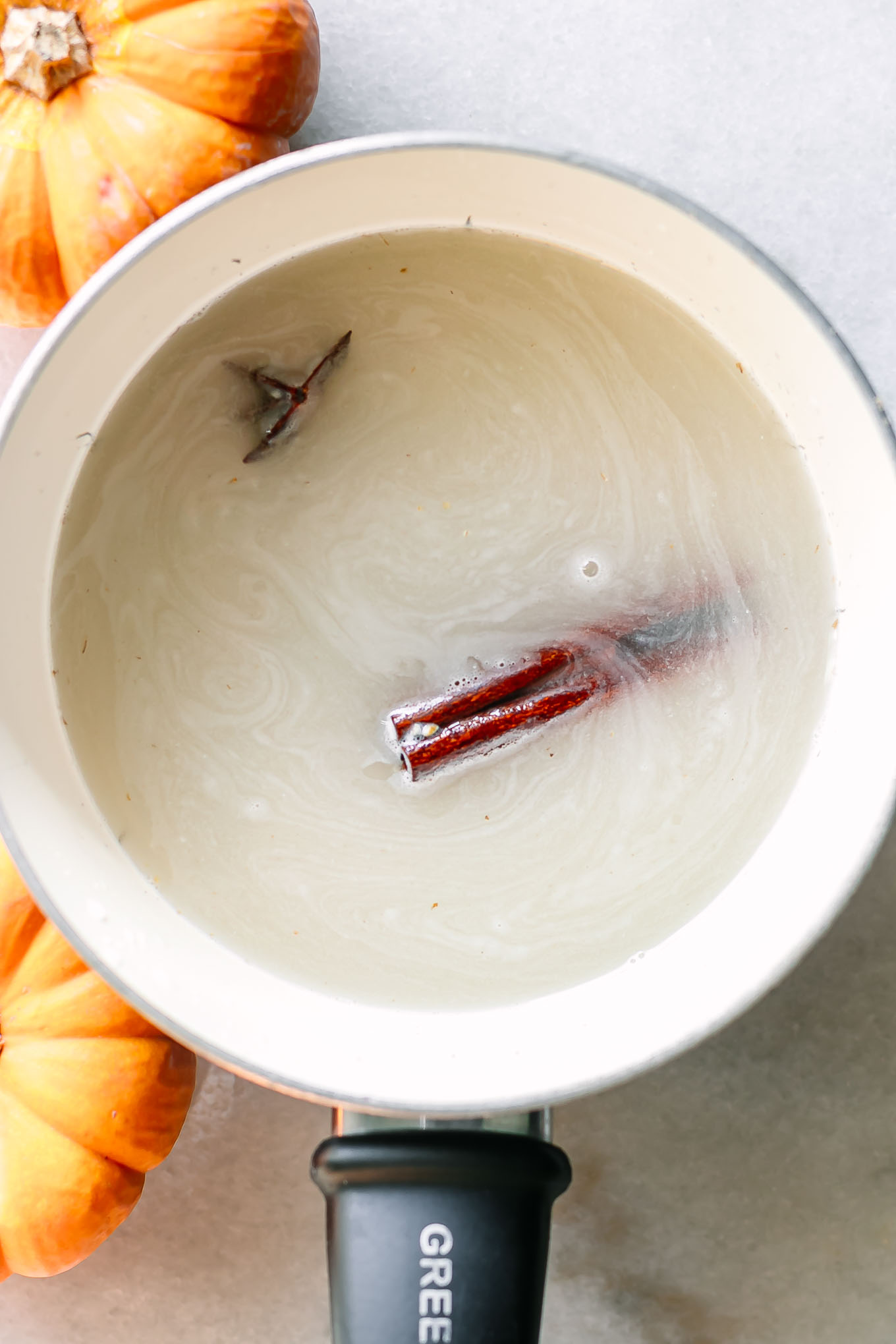 a small white pot with oatmeal and a cinnamon stick