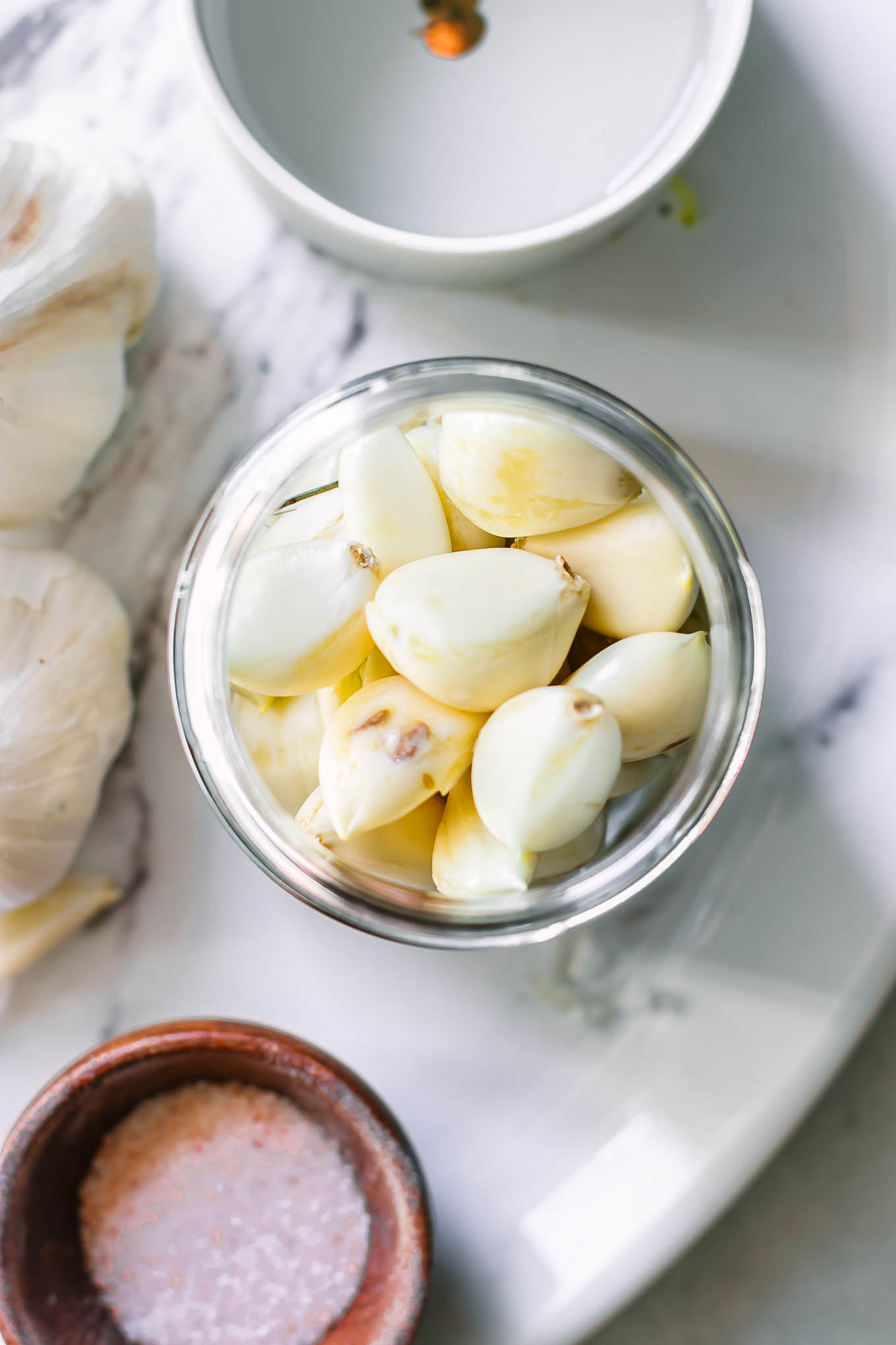 garlic cloves in a pickling jar on a white table