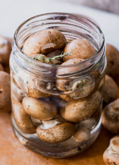 quick pickled mushrooms in a jar with vinegar brine on a wood table