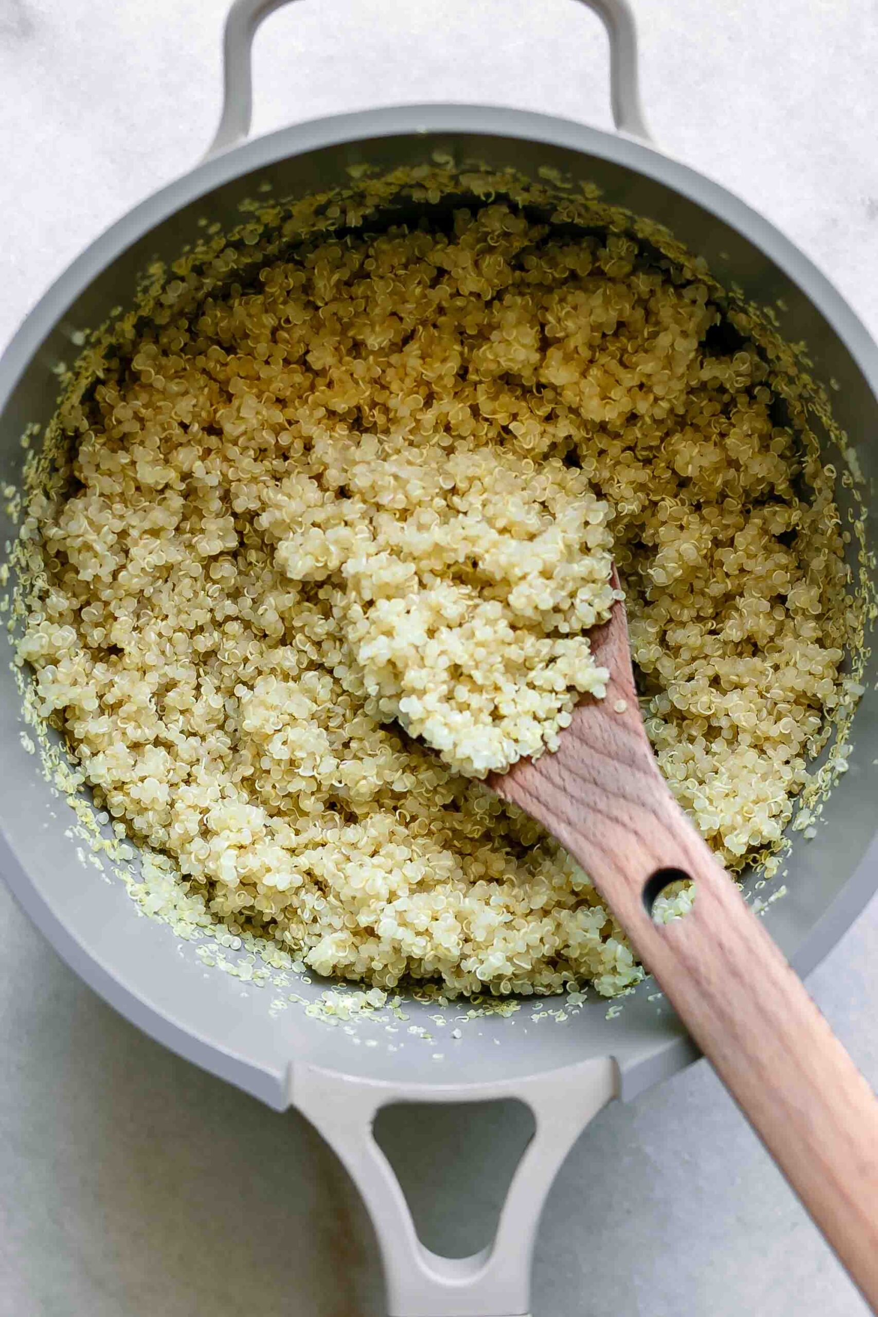 cooked quinoa in a small pot with a wooden spoon