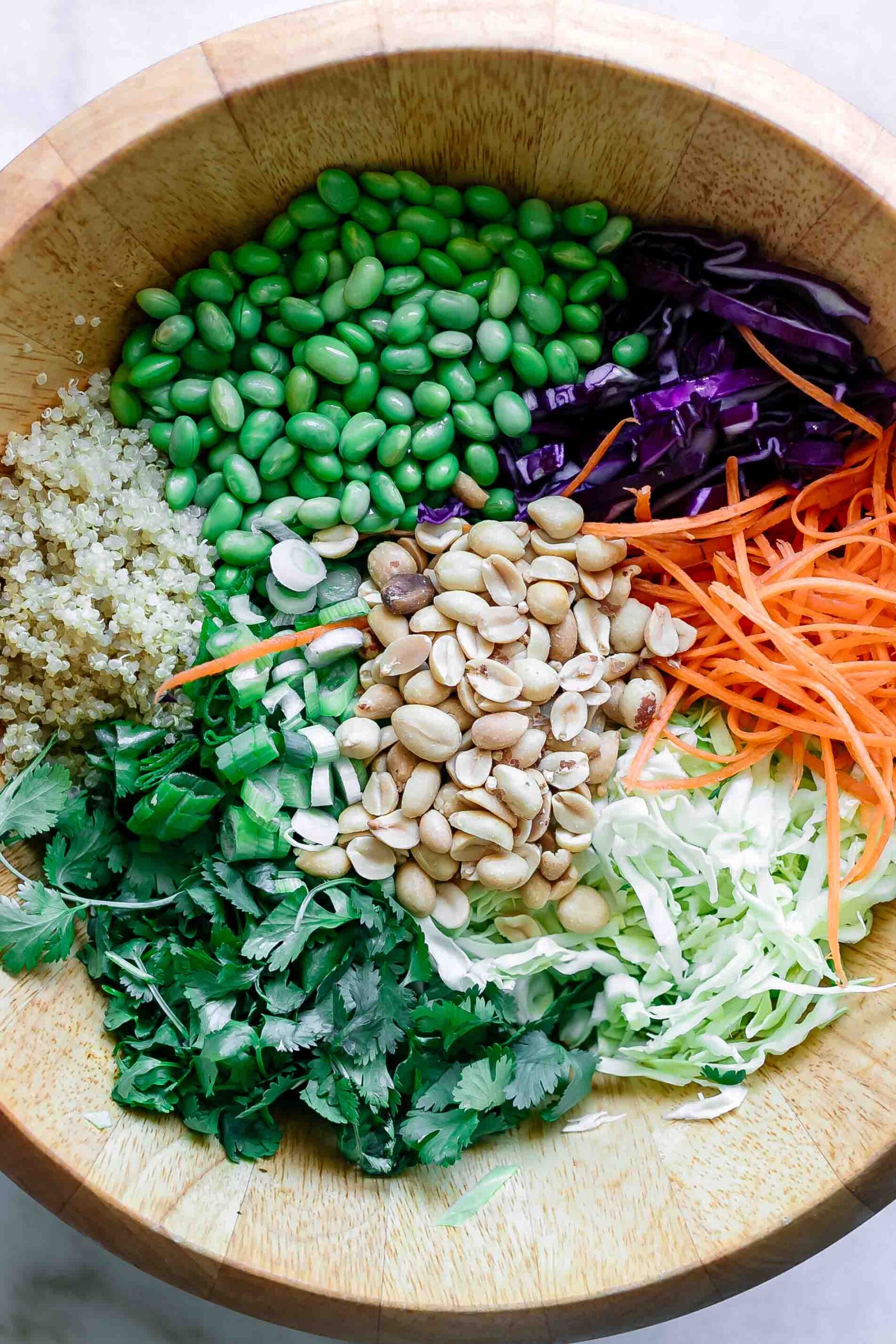 a large salad bowl with cabbage, quinoa, carrots, edamame, peanuts, and cilantro