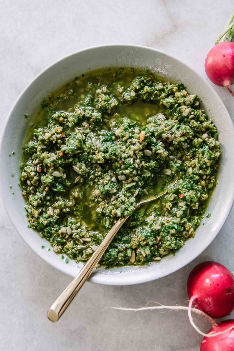 pesto made with radish greens in a white bowl on a white table
