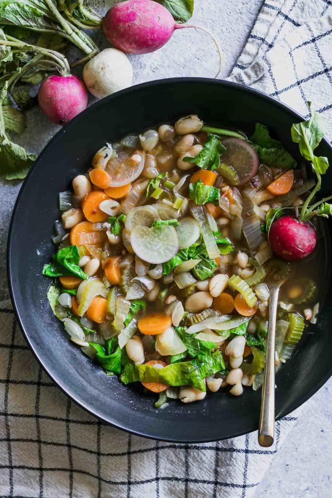 vegetable soup with fresh radish greens on a blue table with a white napkin