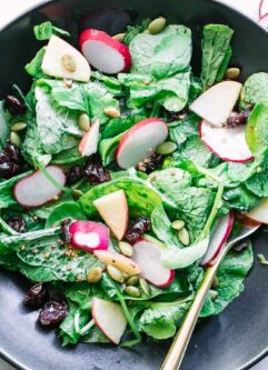 radish greens salad in a black bowl on a white table
