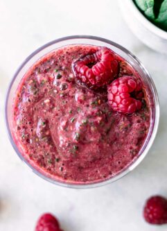a close up of a raspberry and spinach smoothie with two raspberries on top