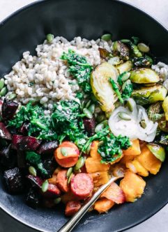 a roasted vegetable barley bowl with garlic herb sauce drizzled on top