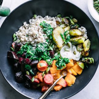 a roasted vegetable barley bowl with garlic herb sauce drizzled on top