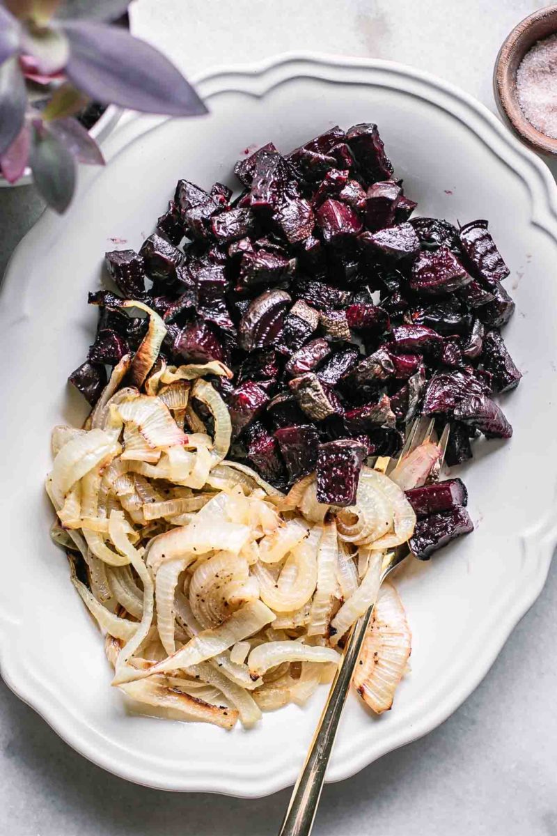 roasted beets and onions on a white serving dish on a white table