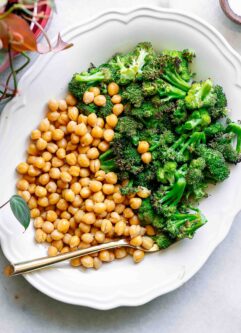 a white plate with roasted chickpeas and broccoli on a white table