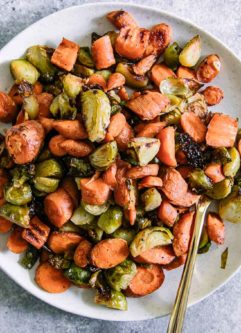 roasted carrots and brussels sprouts on a white p