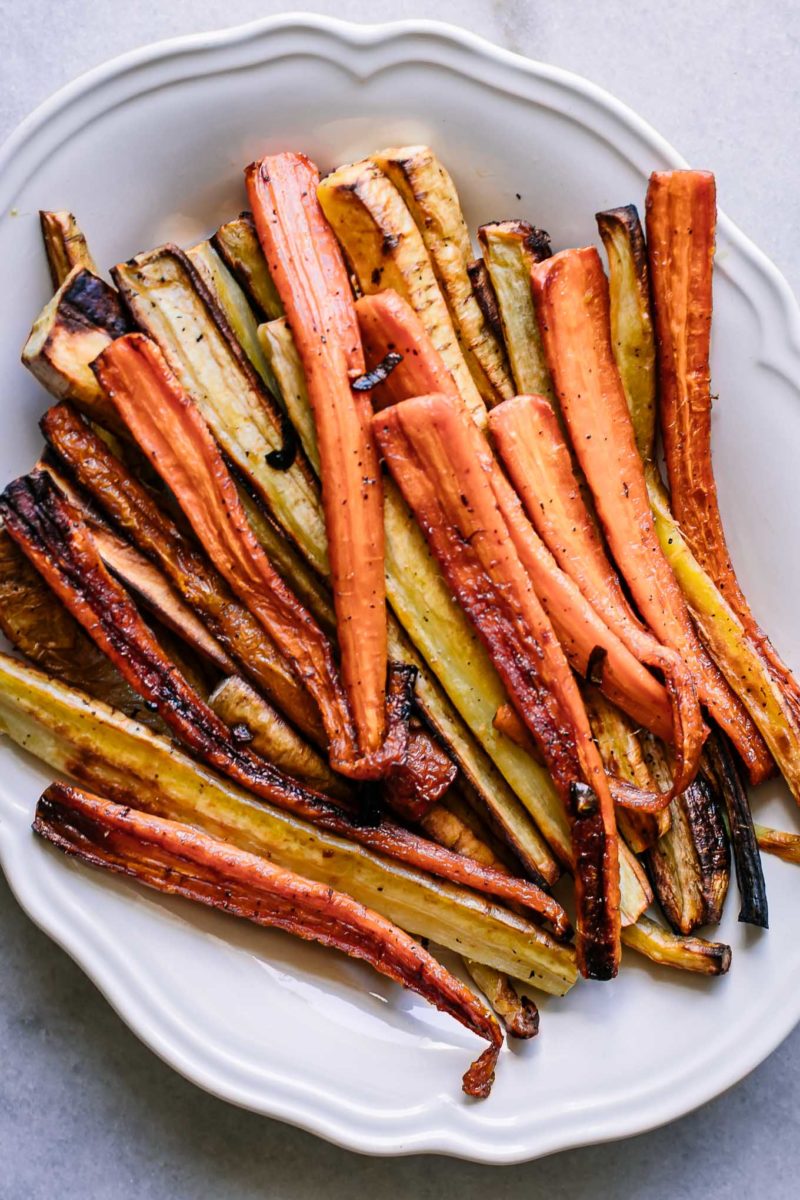 roasted carrot and parsnips on a white plate on a white table