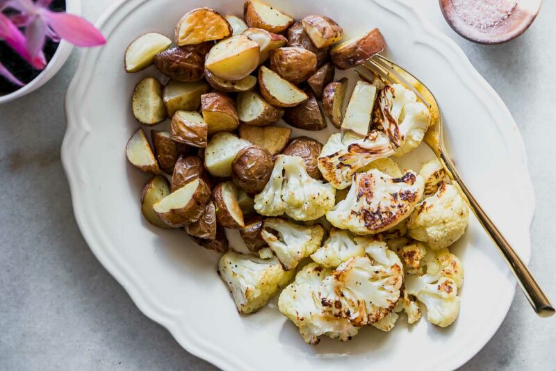roasted cauliflower and potatoes on a white plate with a gold fork