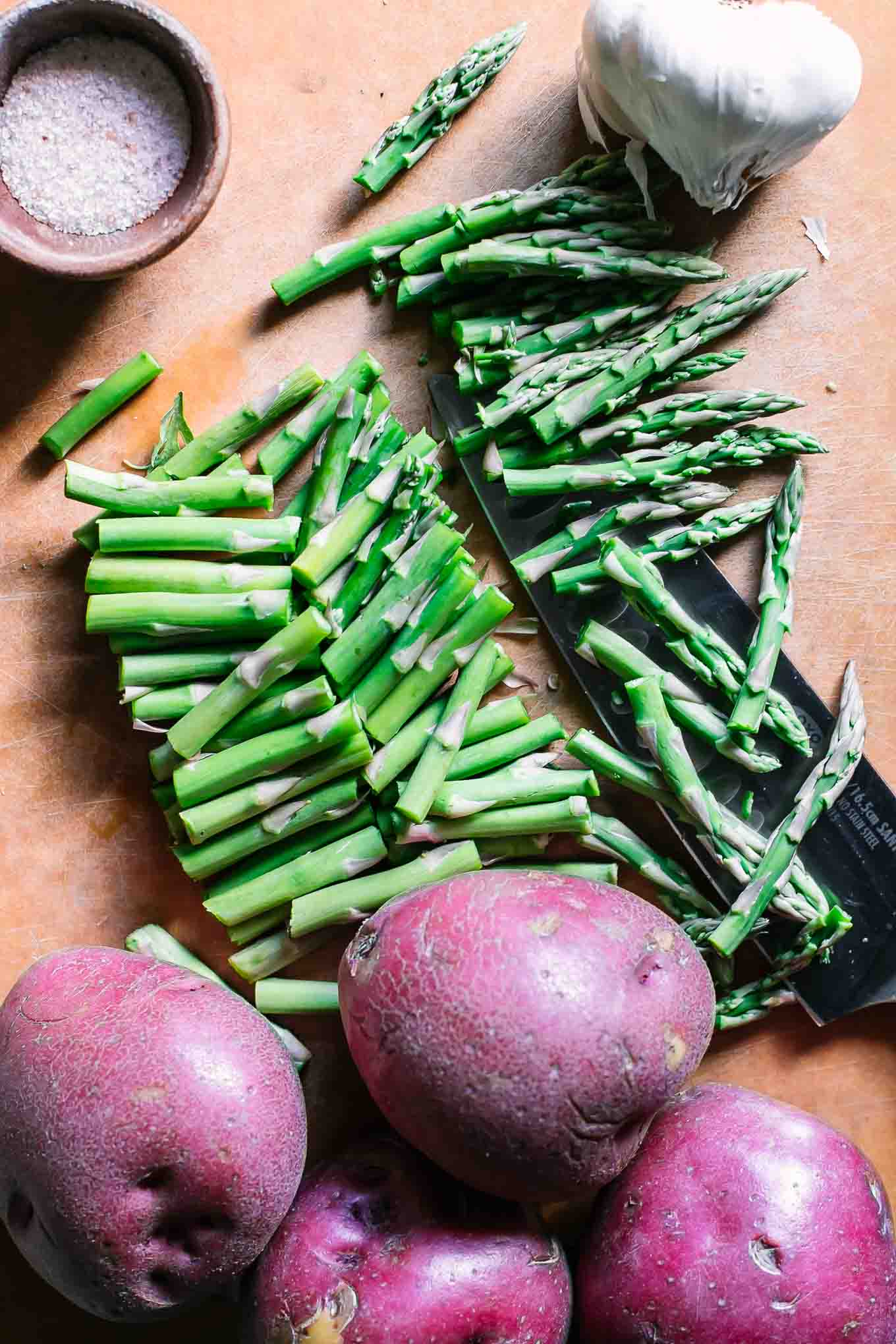 cut asparagus and potatoes on a wood cutting board