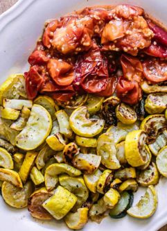 roasted yellows summer squash and tomatoes on a white plate on wood table