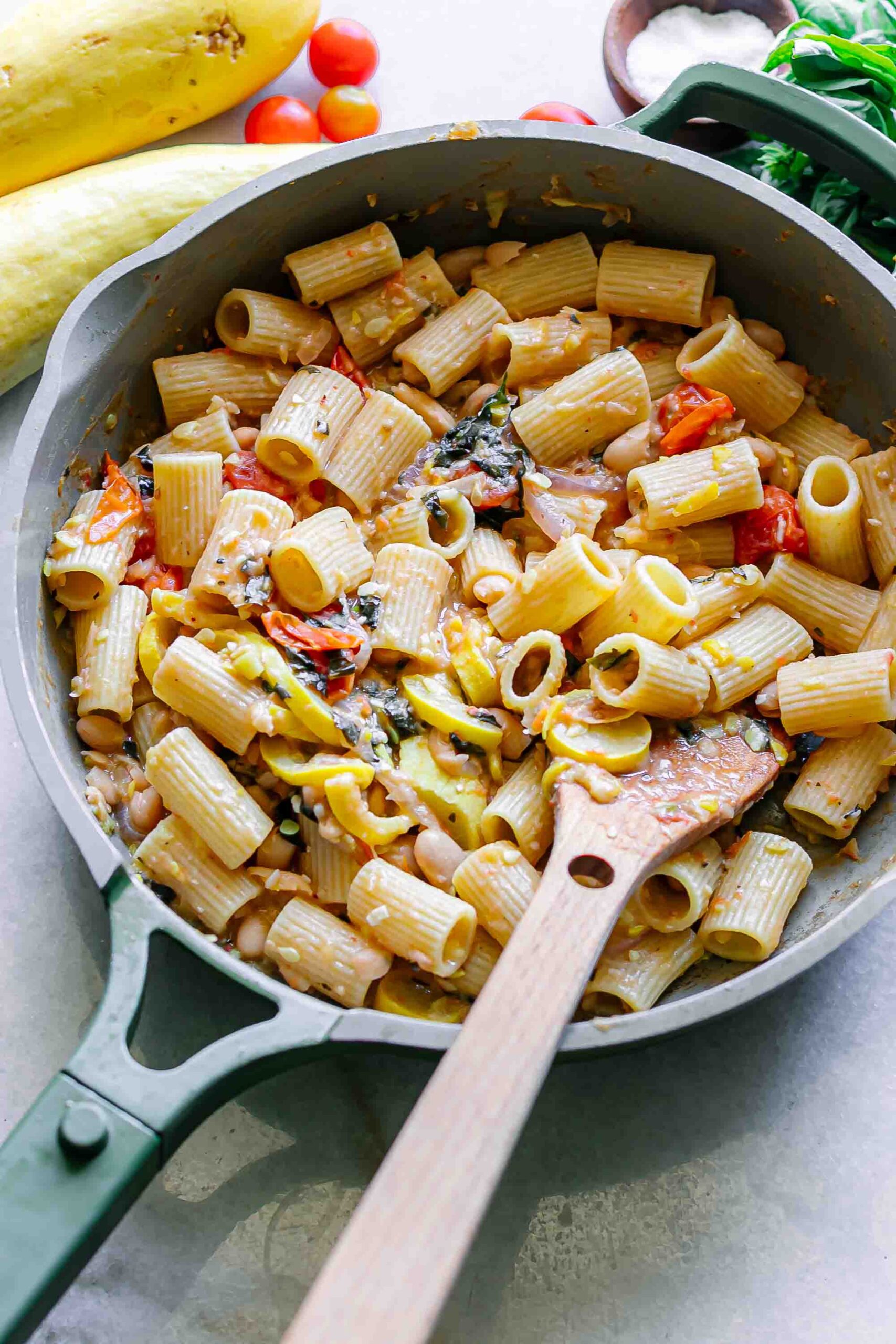a pan of pasta with creamy white bean sauce and roasted vegetables on a white table