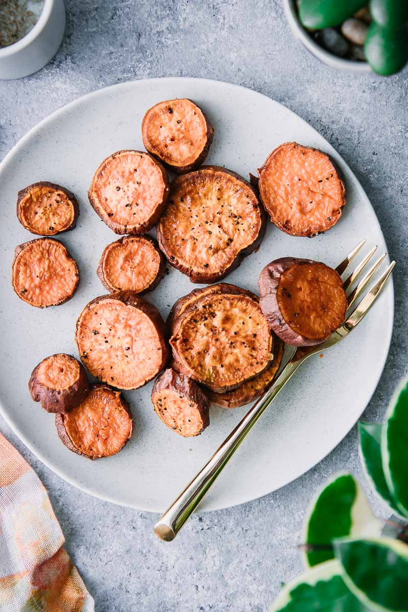 baked sweet potato slices on a white plate on a blue table