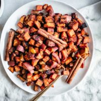 roasted apples and sweet potatoes on a white plate with a gold fork