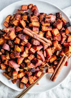 roasted apples and sweet potatoes on a white plate with a gold fork