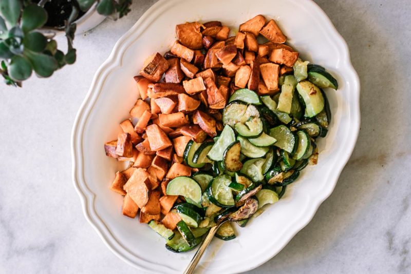 baked sweet potatoes and zucchini side dish on a white table