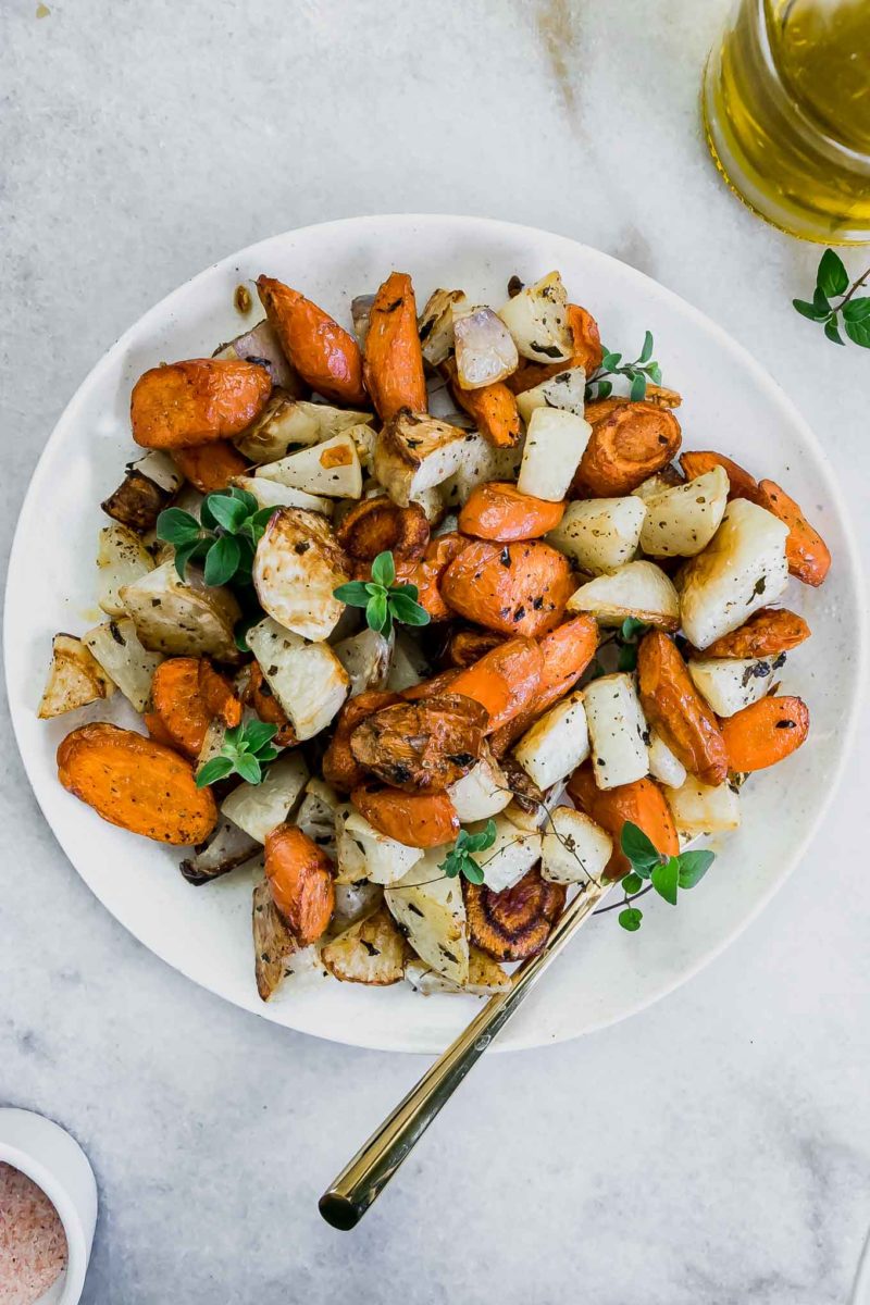 roasted turnips and carrots on a white plate with a gold fork