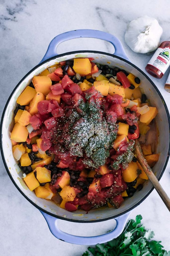 a large soup pot with squash, tomatoes, beans, cumin, oregano, and coriander