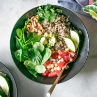 simple quinoa and spinach salad in a black bowl on a white table