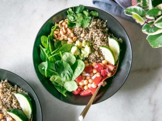 simple quinoa and spinach salad in a black bowl on a white table