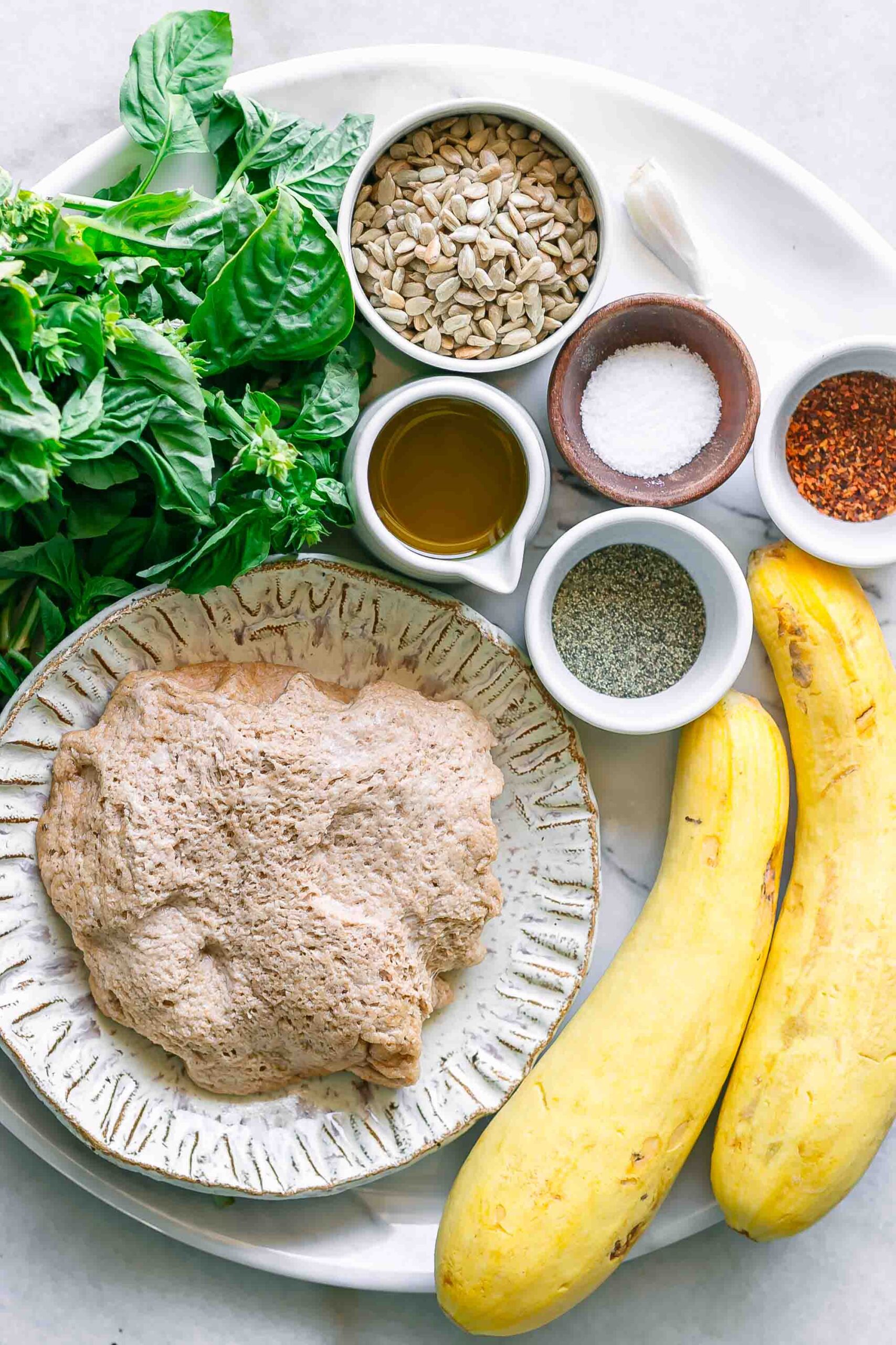 pizza dough, yellow squash, basil, sunflower seeds, corn, and spices for a pizza