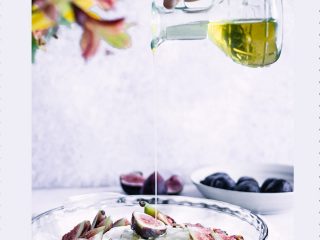 A hand drizzling maple syrup over a pie dish with figs and the words "baked brie with figs and maple" in black writing.