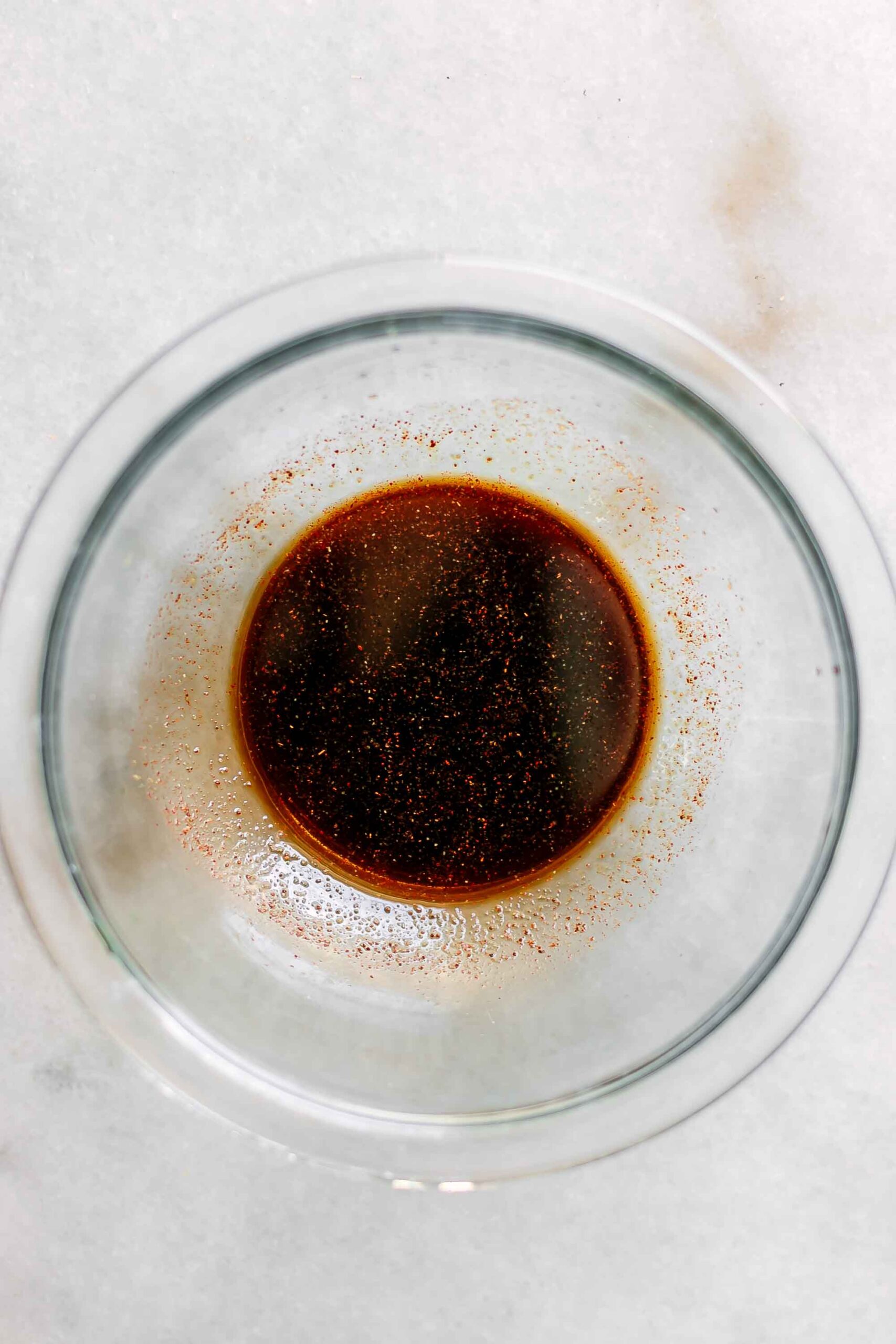 a bowl of smokey sauce to flavor tempeh bacon on a white table