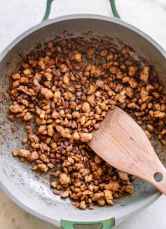 tempeh bacon bits in a pan after cooking with a wooden spoon