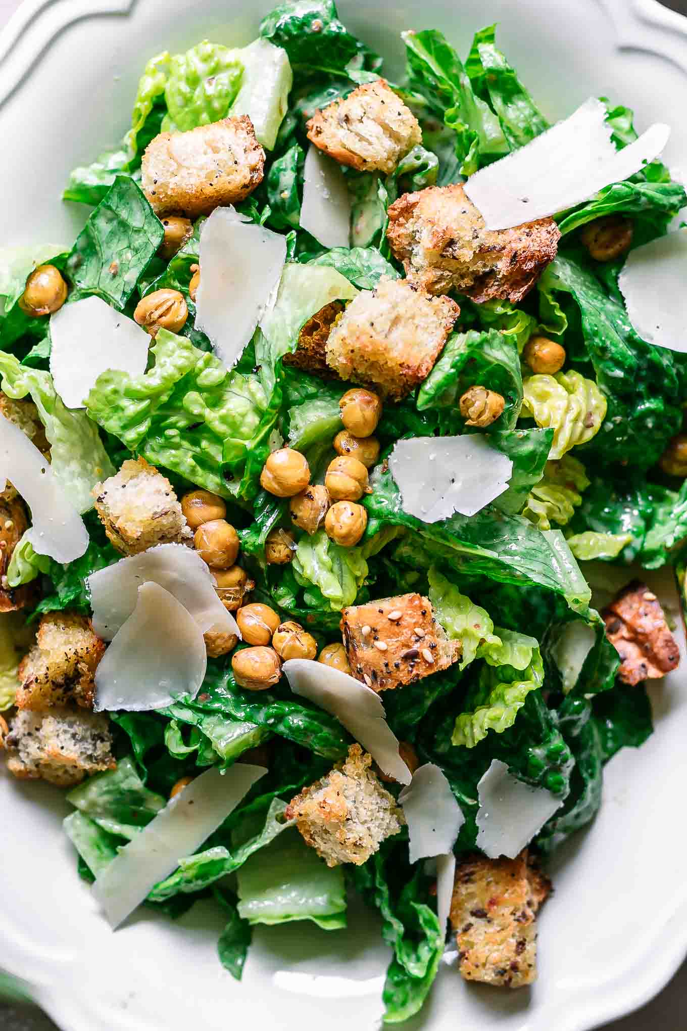 a close up photo of a vegan caesar salad on a white plate