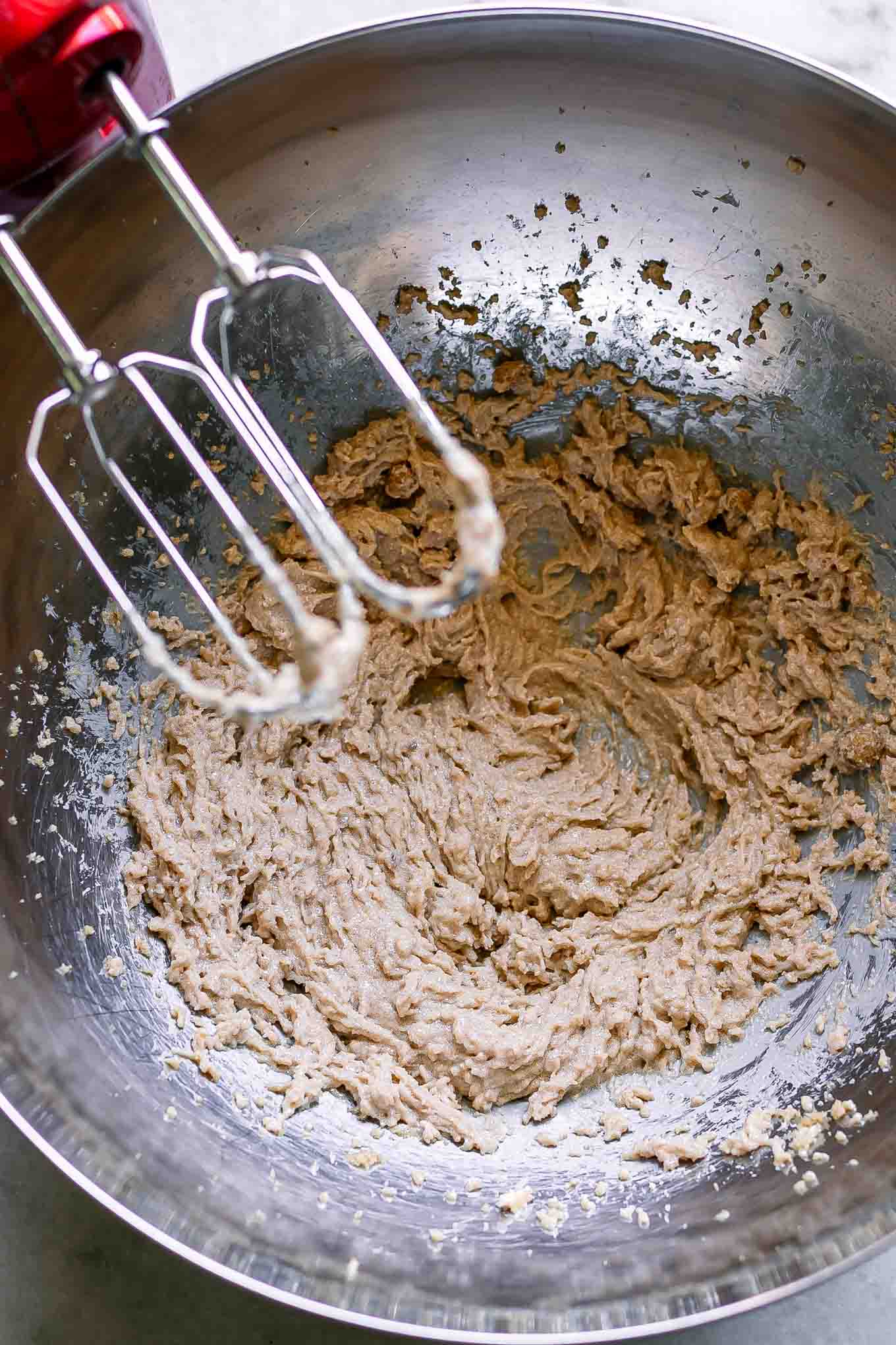 whipped butter and brown sugar in a metal bowl on a table with a handheld kitchen mixer