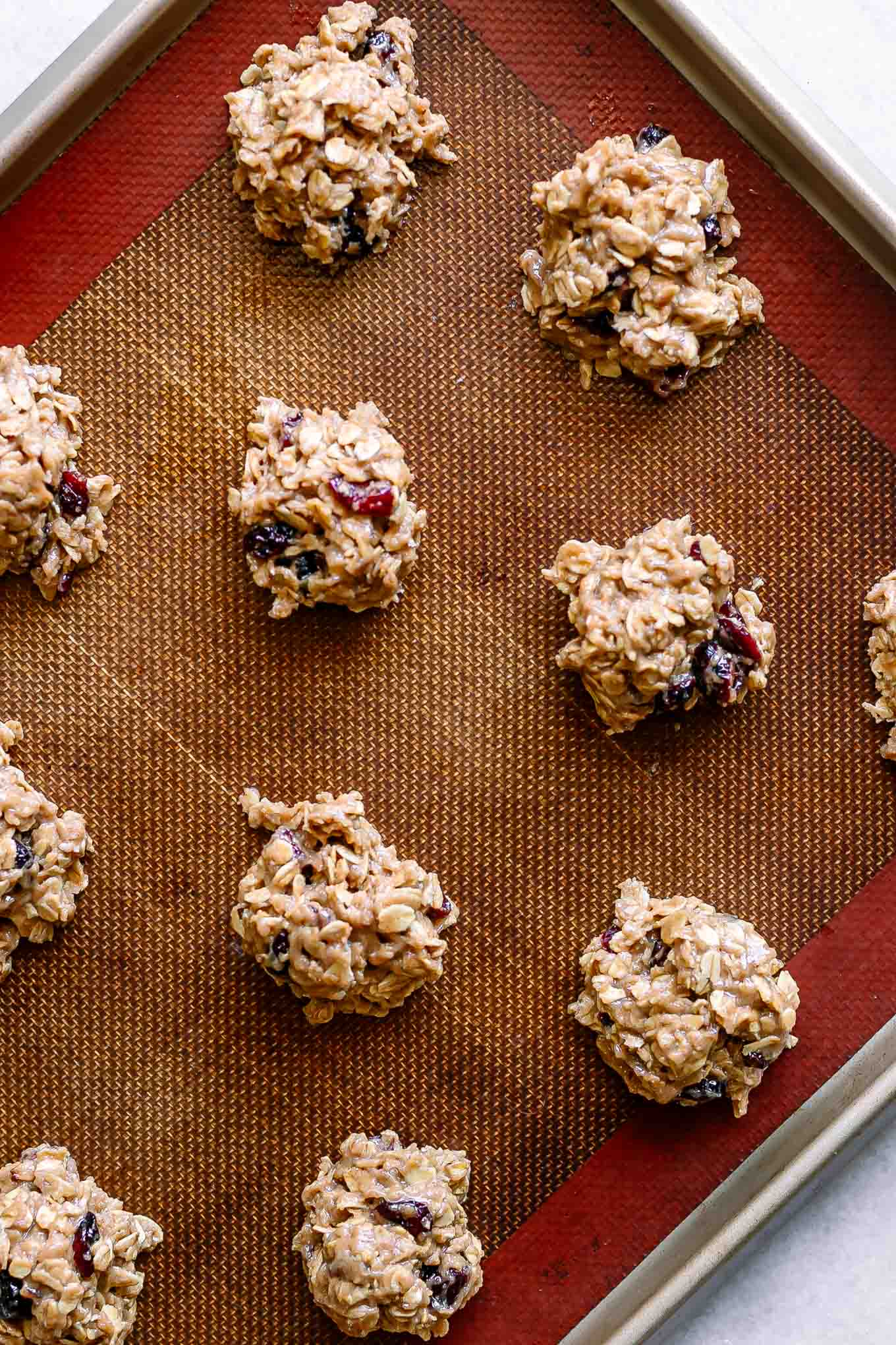 vegan oatmeal cookie dough with cranberries on a baking sheet before baking