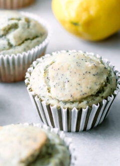 vegan lemon poppyseed muffins on a white table with fresh lemons