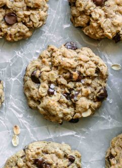 vegan oatmeal chocolate chip cookies on a white table with a bowl of chocolate chips
