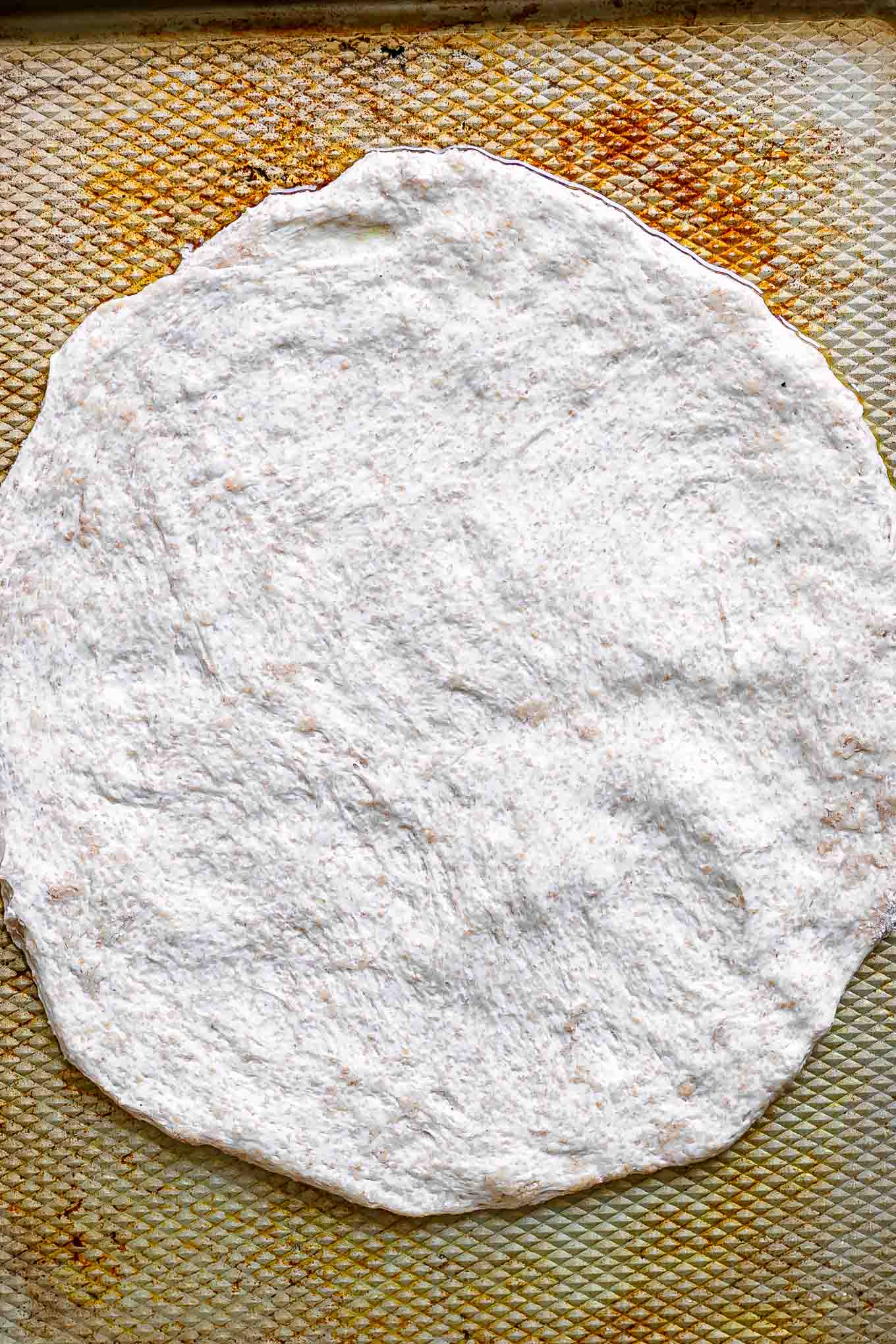 pizza dough spread out on a baking sheet
