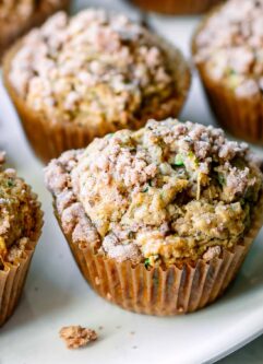 vegan zucchini muffins with a crumb topping on a white table