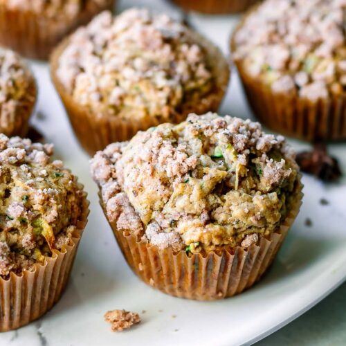vegan zucchini muffins with a crumb topping on a white table