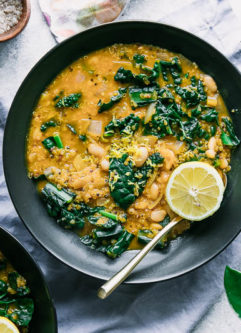 a bowl of white bean chili or soup on a table with a blue napkin and a green plant