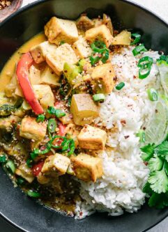 a yellow curry tofu bowl with white rice on a white table